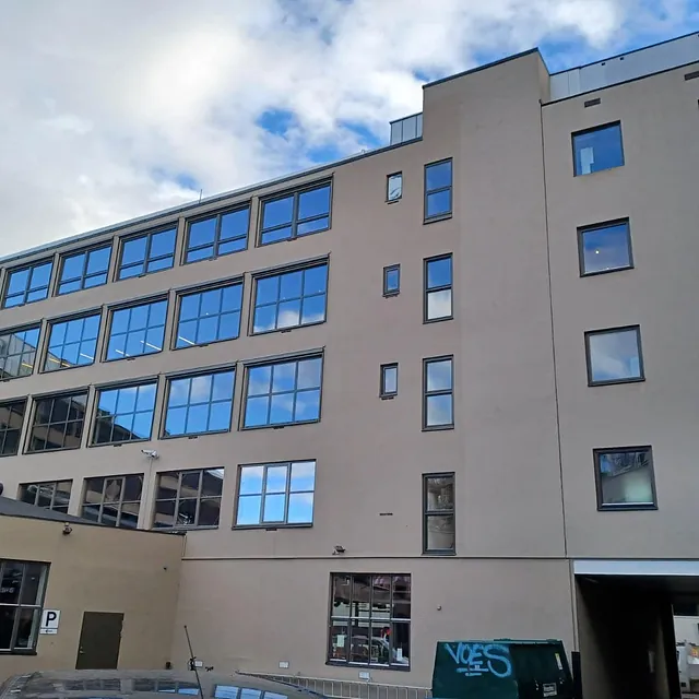 Stor bygård med mange vinduer som reflekterer himmelen etter rengjøring.